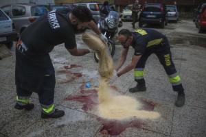 Personale di una ditta di manutenzione delle strade del Comune di Napoli sparge segatura sulle chiazze di sangue nel luogo in cui Domenico Aporta, 24 anni, con precedenti penali e ritenuto vicino al clan di camorra "Vinella Grassi", e' stato ucciso con almeno un colpo di arma da fuoco alla testa nella notte a San Pietro a Patierno, alla periferia di Napoli, 17 ottobre 2015. Nell'agguato, il fratello Mariano, di 21 anni, incensurato, è rimasto ferito ad un braccio.