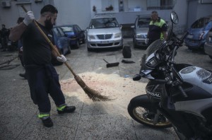 Un dipendente di una società di manutenzione delle strade del Comune di Napoli rimuove la segatura che copre le macchie di sangue di Domenico Aporta, 24 anni, con precedenti penali e ritenuto vicino al clan di camorra "Vinella Grassi", ucciso con almeno un colpo di arma da fuoco alla testa nella notte a San Pietro a Patierno, alla periferia di Napoli, 17 ottobre 2015. Nell'agguato, il fratello Mariano, di 21 anni, incensurato, è rimasto ferito ad un braccio.