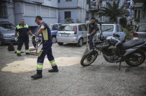 Operatori di una ditta di manutenzione strade del Comune di Napoli rimuovono le macchie di sangue nel luogo in cui Domenico Aporta, 24 anni, con precedenti penali e ritenuto vicino al clan di camorra "Vinella Grassi", e' stato ucciso con almeno un colpo di arma da fuoco alla testa nella notte a San Pietro a Patierno, alla periferia di Napoli, 17 ottobre 2015. Nell'agguato, il fratello Mariano, di 21 anni, incensurato, è rimasto ferito ad un braccio.