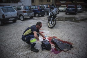 Un operatore ecologico napoletano rimuove le tracce di sangue dell'agguato in cui Domenico Aporta, 24 anni, con precedenti penali e ritenuto vicino al clan di camorra "Vinella Grassi", e' stato ucciso con almeno un colpo di arma da fuoco alla testa nella notte a San Pietro a Patierno, alla periferia di Napoli, 17 ottobre 2015. Nell'agguato, il fratello Mariano, di 21 anni, incensurato, è rimasto ferito ad un braccio.