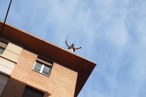 Un occupante posizionato in cima a uno stabile, mentre in strada avvengono scontri tra manifestanti e agenti di polizia a Bologna, dove è in corso lo sgombero di un immobile occupato abusivamente in via Irnerio