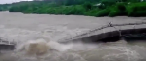 Il fiume in piena inghiotte il ponte: fuga disperata di due persone (video)